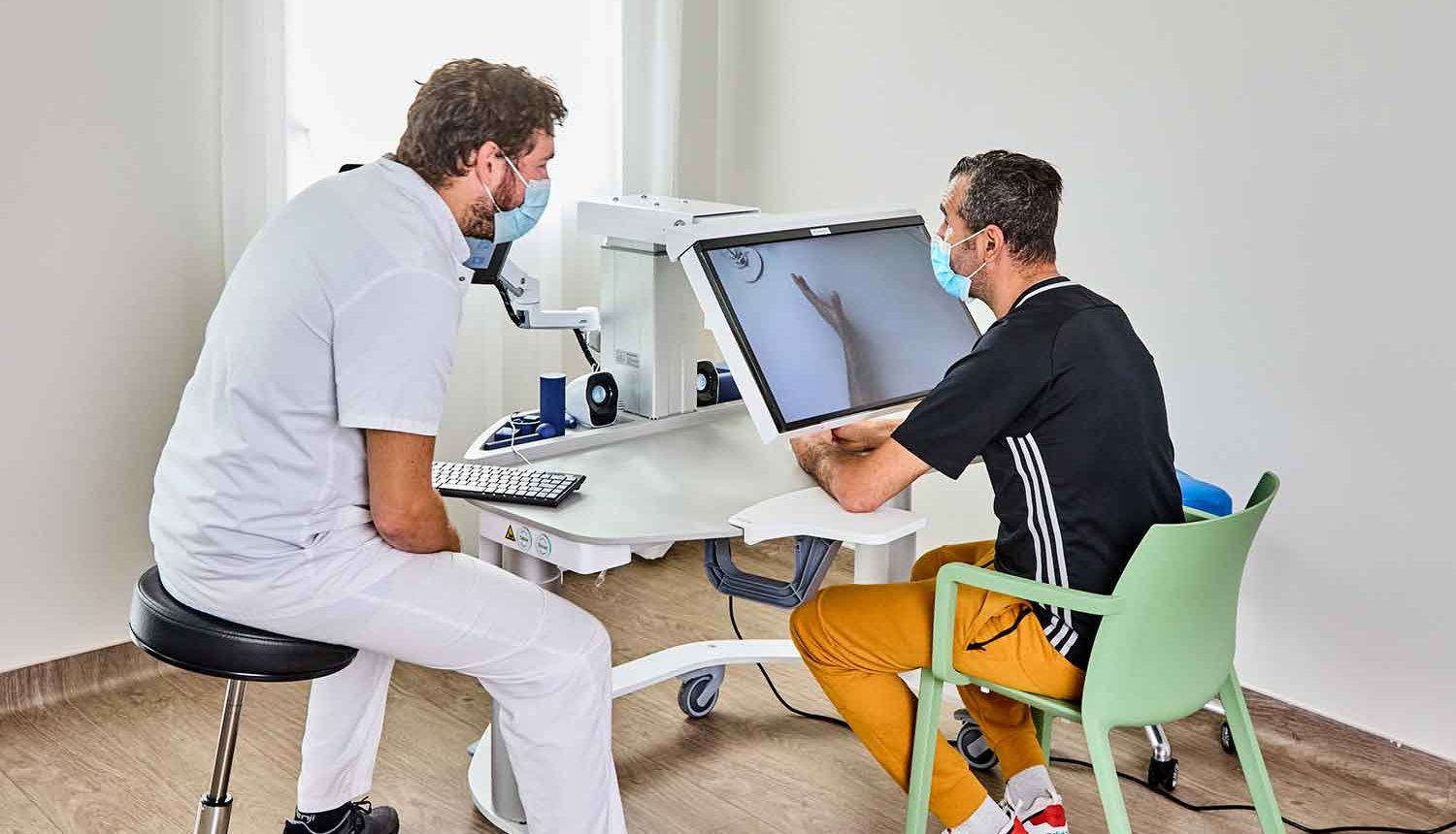Infirmier guidant son patient en tenue de sport sur une machine médicale